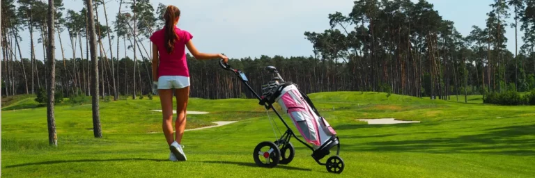 Vrouwelijke golfer op golfbaan met golftrolley