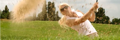 vrouwelijke golfer die uit een bunker speelt